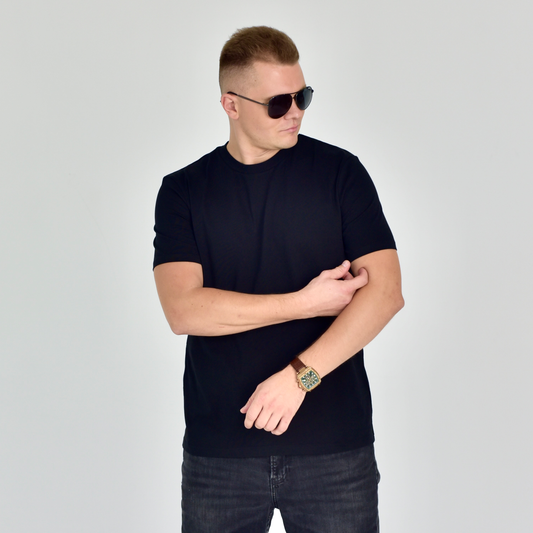 Stilingas vyras dėvi klasikinius juodus Designedbyme.lt marškinėlius, akinius nuo saulės ir laikrodį. Modernus ir universalus drabužis tinka įvairioms progoms. Organinės medvilnės kokybė užtikrina komfortą. Puiki dovana jam ar jai. Populiarus pasirinkimas tarp marškinėlių mėgėjų, Balti marškinėliai ir Juodi marškinėliai