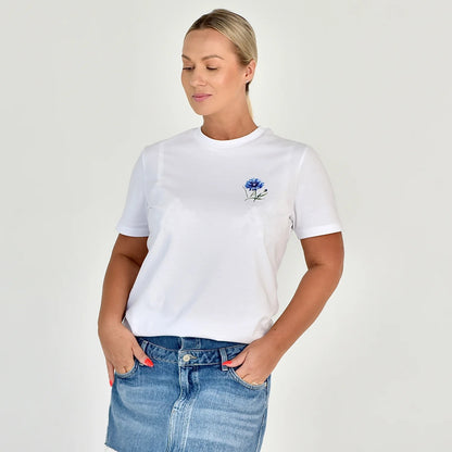 Moteriški marškinėliai “Rugiagelė” – subtilus baltų marškinėlių dizainas su ryškia rugiagėlės gėle krūtinėje.