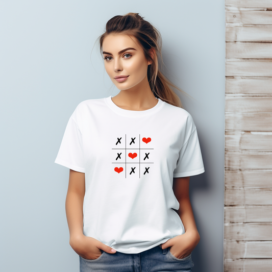 Balti moteriški marškinėliai "Love Game" su kryžiukų ir nuliukų žaidimo dizainu, papuošti raudonomis širdelėmis. Minimalistinis, žaismingas dizainas ant klasikinio apvalios apykaklės marškinėlių modelio.